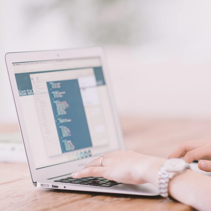 The image shows a open laptop with a hand hovering over the keyboard